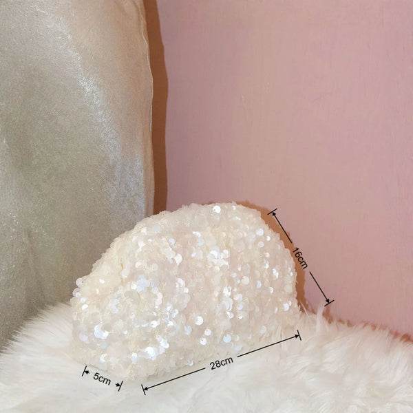 Pochette à l'épaule en perles blanches et moelleuses posée sur un mur rose.