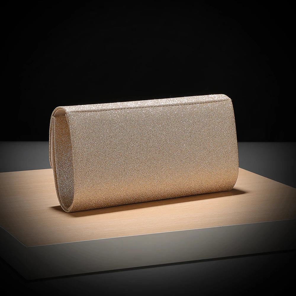 A rectangular envelope clutch covered in gold sequins resting on a wooden surface.