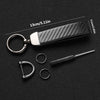 A black carbon fiber leather keychain with a silver ring and a small metal tool.