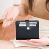 A hand holds a black minimalist RFID blocking wallet with a gold chain, demonstrating card protection.