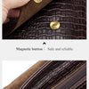 Nahaufnahme einer dunkelbraunen Lederhandtasche mit magnetischer Knopfs und echtem Lederkettendetail.