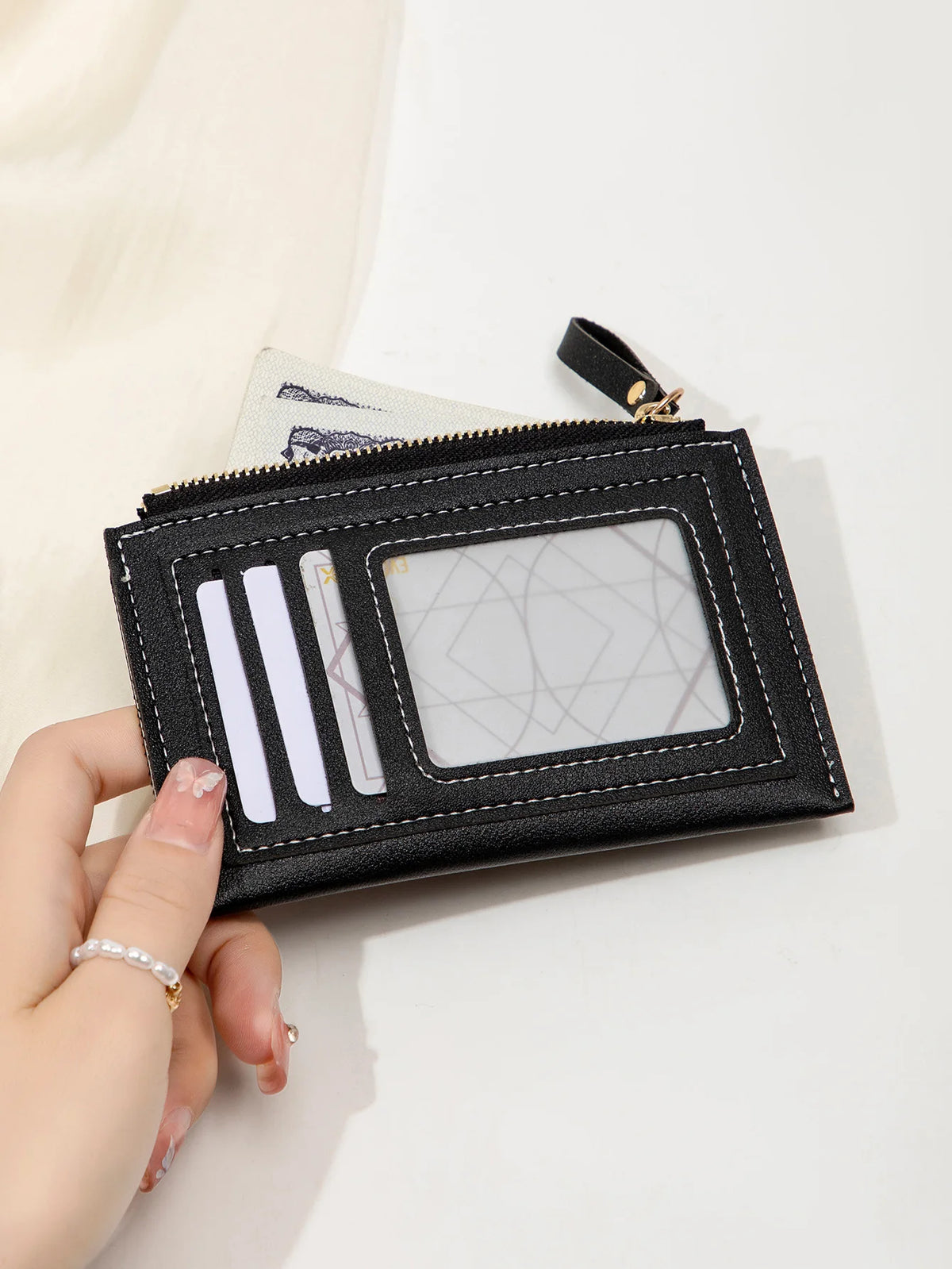 Portefeuille en cuir PU noir minimaliste avec fenêtre transparente et fentes pour cartes, tenu dans une main.