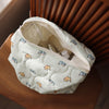 A cream-colored quilted cosmetic storage pouch with a light blue cat print, resting on a wooden surface.
