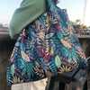 A close-up of a patterned fabric shopping tote bag carried by a person outdoors.