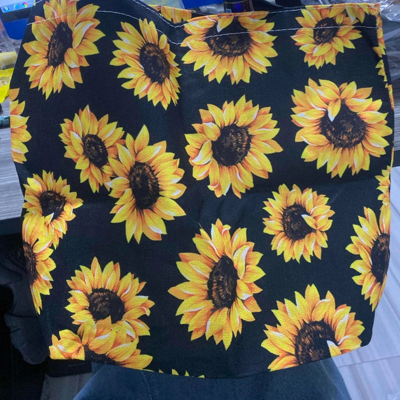 Black canvas tote bag featuring a vibrant yellow sunflower print.