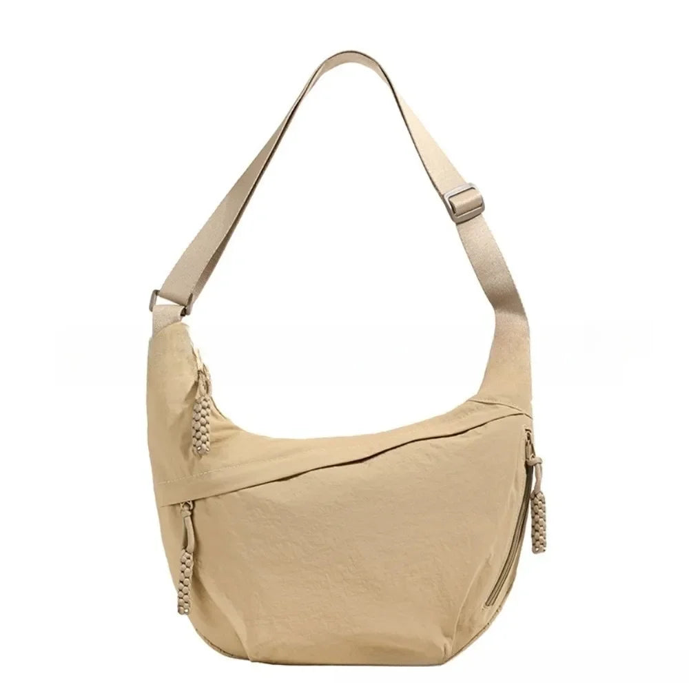 A beige canvas crossbody bag with adjustable straps and drawstring details.