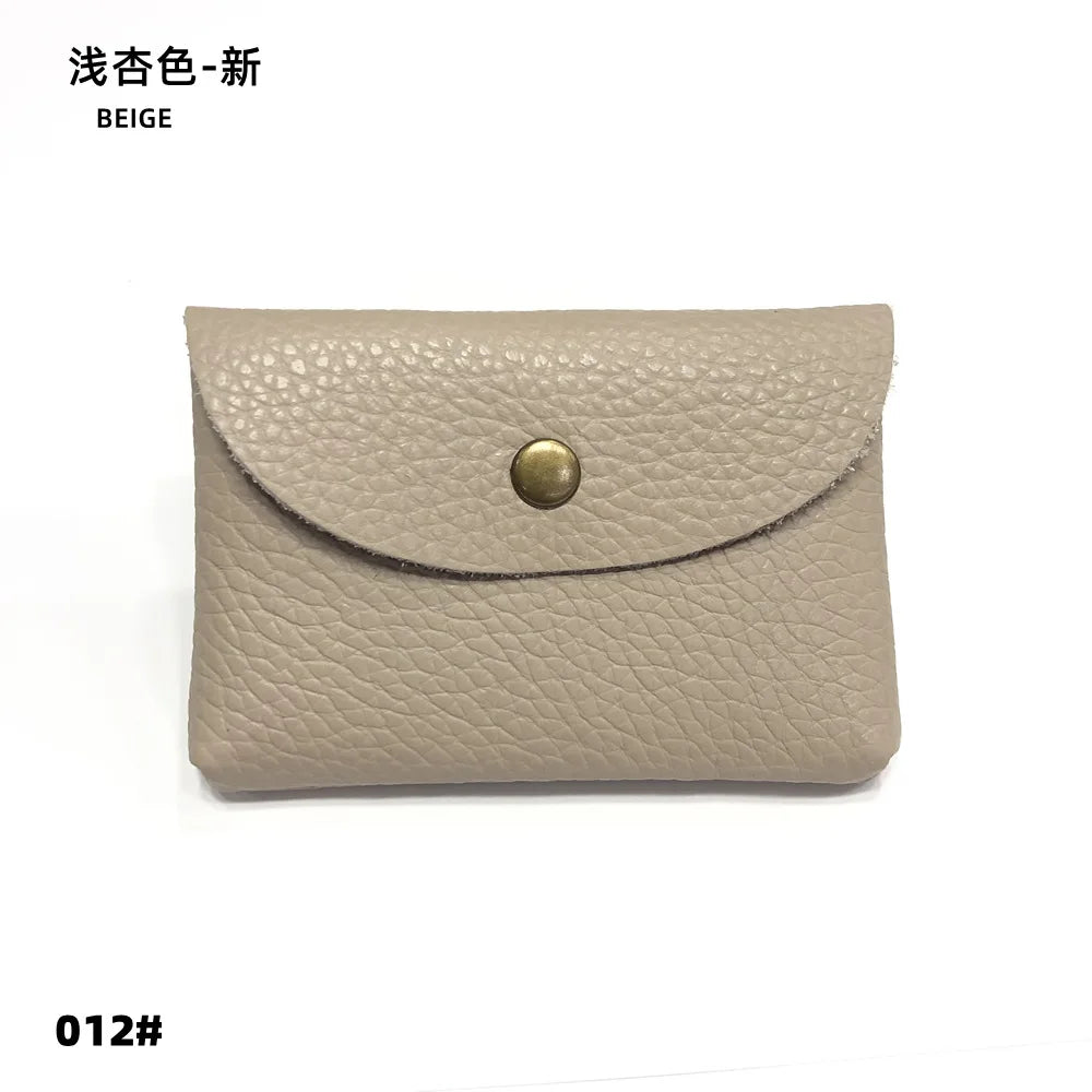 A beige genuine leather card holder or coin purse with a gold-toned stud closure.