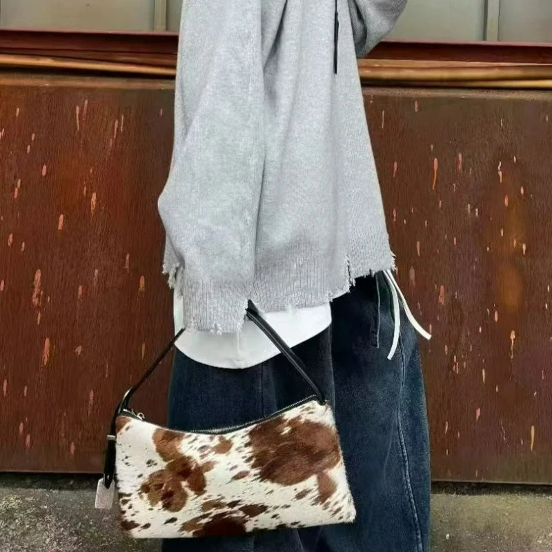 A close-up of a vintage horsehair and cowhide crossbody bag worn by a person, featuring brown and white patterns.