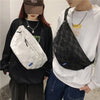 Eine Person in einem schwarzen Hoodie hält eine weiße karierte Brusttasche vor einer Person in einem weißen Langarmshirt