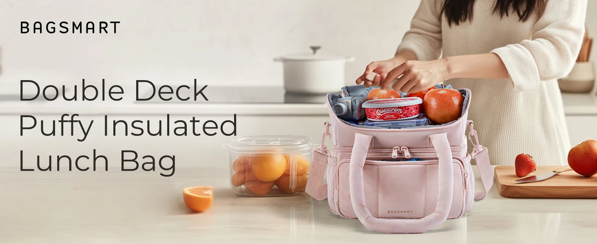 A pink insulated lunch bag is shown next to fresh fruit on a light countertop.