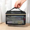 A hand is opening a large capacity black mesh travel cosmetic storage pouch with a gold trim.