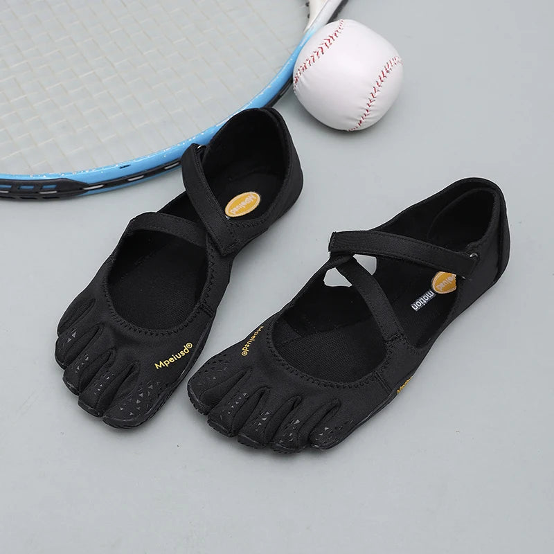 Black women's barefoot five-toe shoes with an adjustable strap and a baseball nearby.