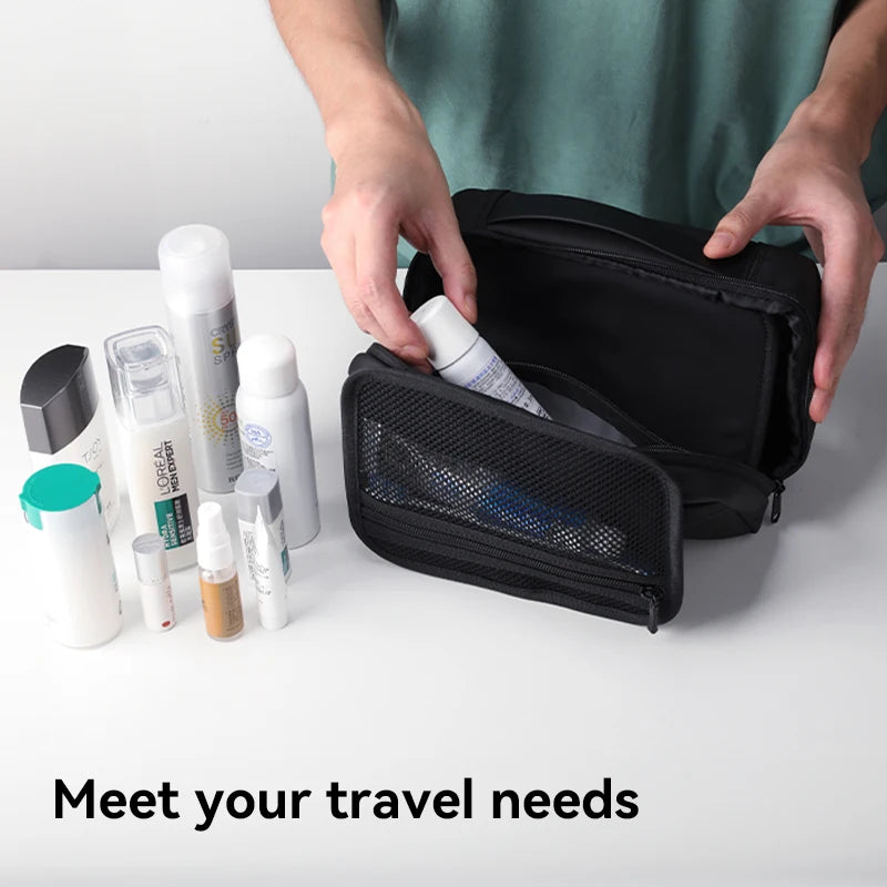 A hand is opening a black toiletry organizer bag, revealing various skincare and grooming products inside.