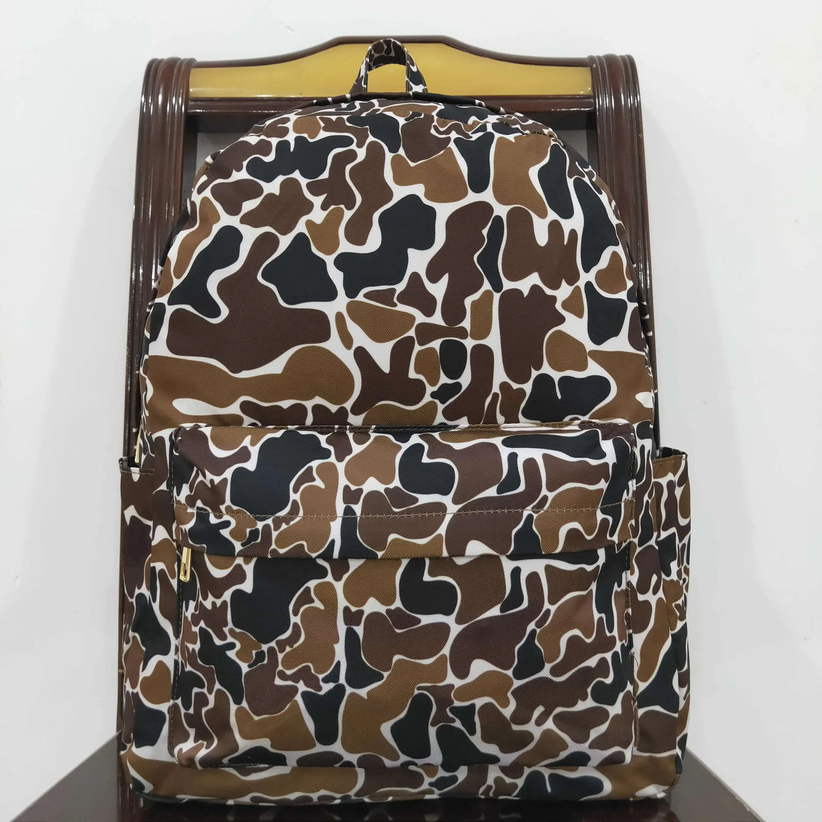 A brown and white camouflage patterned toddler backpack with a wooden frame.