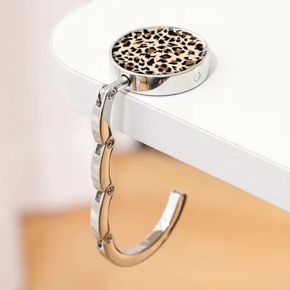 A round metal bag hanger with a leopard print insert is displayed on a white surface.