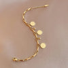 A gold stainless steel charm bracelet featuring a portrait pendant and various circular charms.