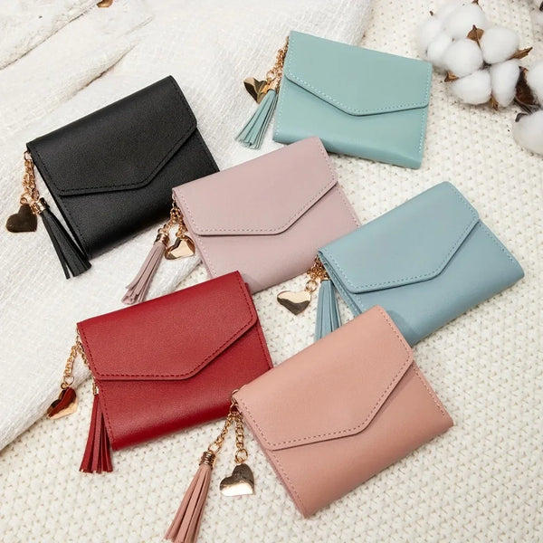 A collection of five PU leather women's coin clutch wallets in shades of black, mint green, pink, and blue, displayed on a wh
