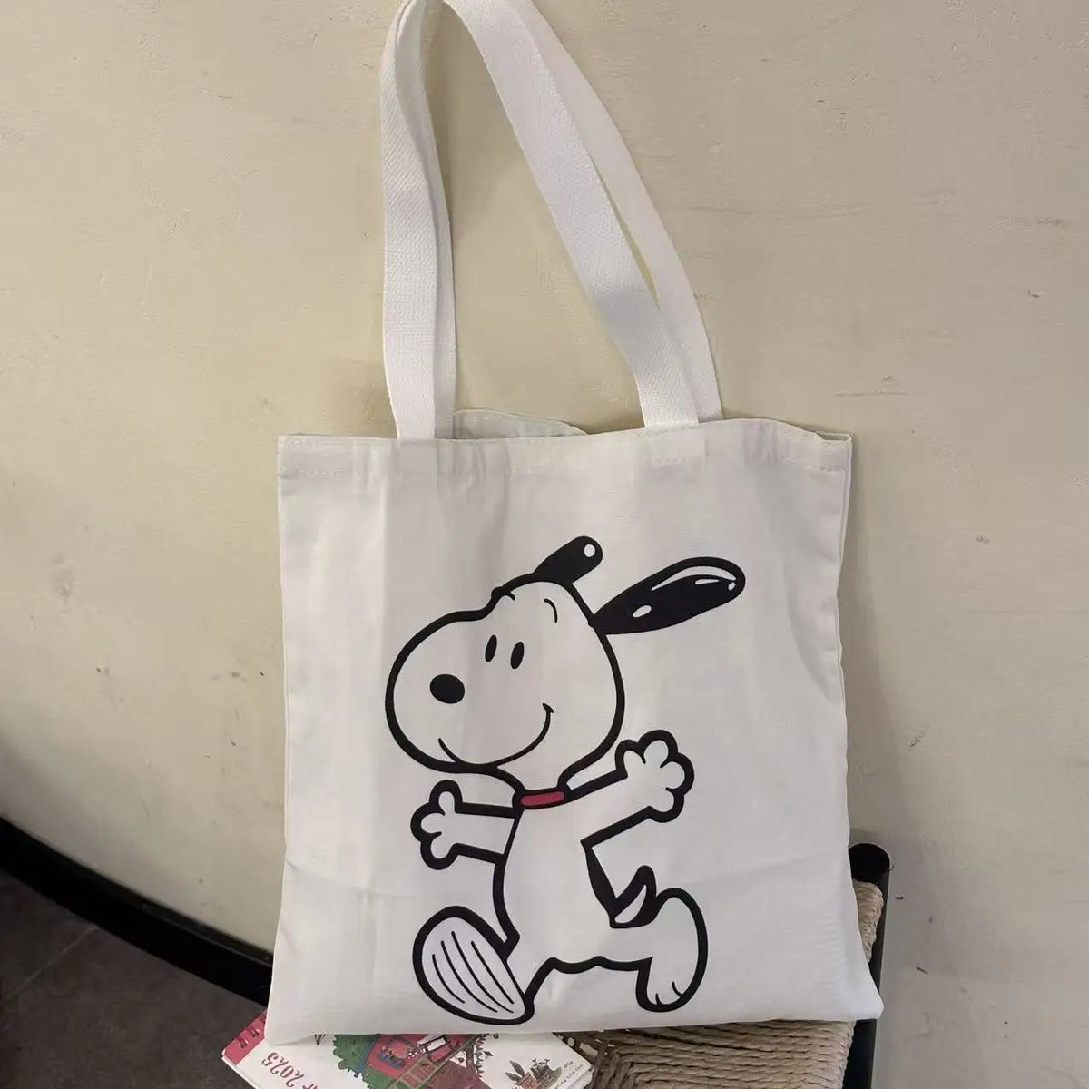 White canvas shoulder bag featuring a black line drawing of Snoopy