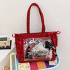 A red woven shoulder tote bag with a transparent front featuring a collage of accessories and items.