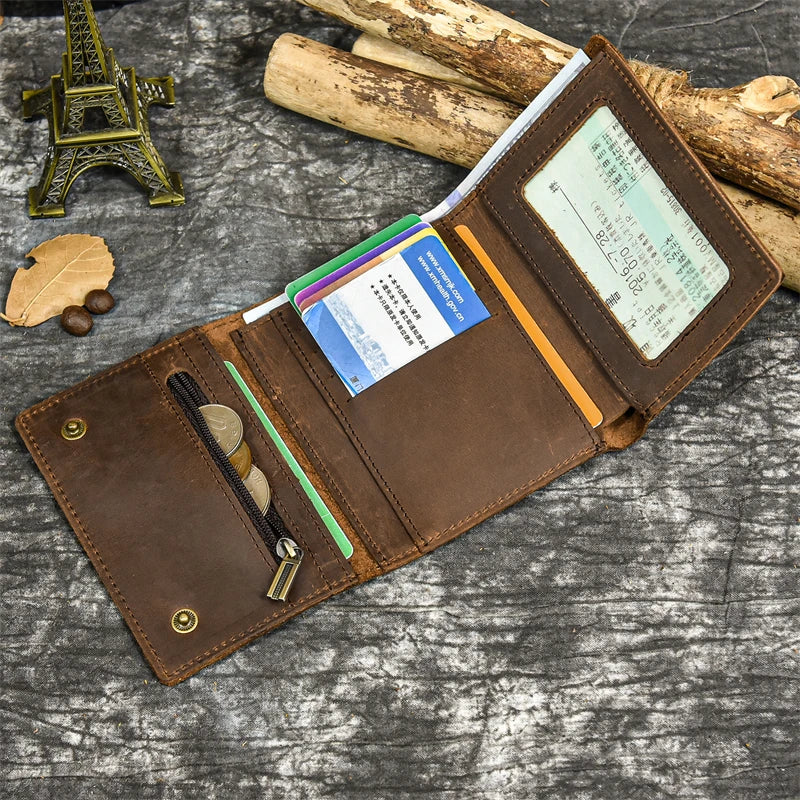 A brown leather trifold wallet with a detachable chain and various cards is shown on a gray textured surface.