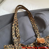 A close-up of a brown leopard print casual tote bag strap against a gray fabric background.