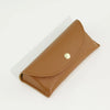 A brown PU leather hard shell sunglasses case lying flat on a white surface.