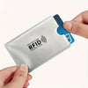 A hand holds a silver RFID protection card sleeve with a blue card inside.