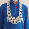 A man wearing a blue hoodie with a red zipper, displaying a chunky gold acrylic Cuban link necklace.