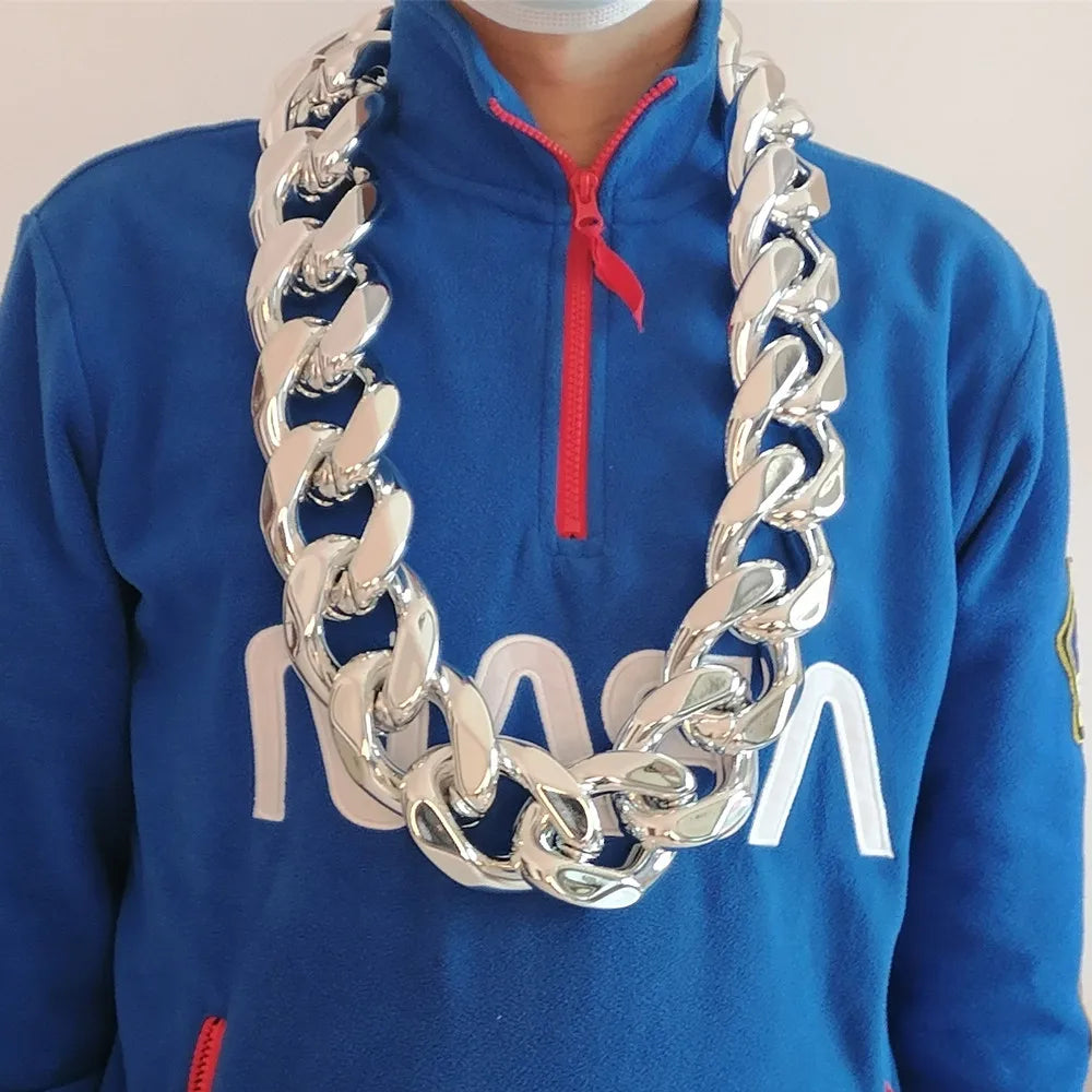 A man wearing a blue hoodie with a red zipper, displaying a chunky gold acrylic Cuban link necklace.