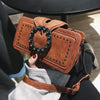 A brown vintage PU leather crossbody bag with a rhinestone buckle is being held by a person.