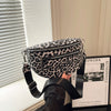 A woman holds a black leopard print PU leather crossbody bag with an adjustable strap in a bright room.
