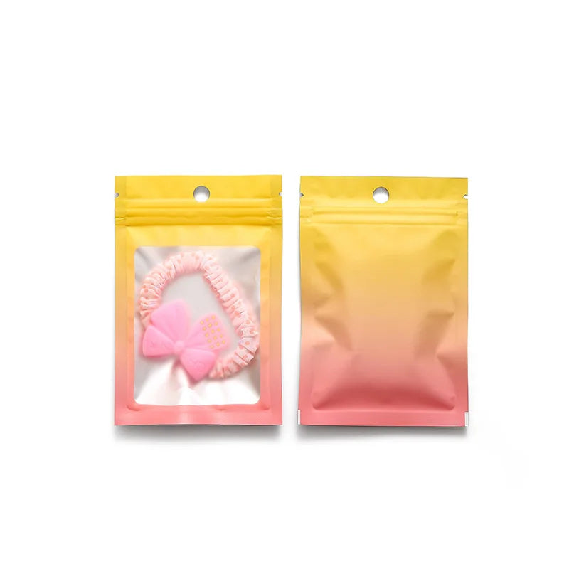 Two resealable gradient storage bags, one pink and yellow, containing jewelry or supplies.