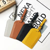 A collection of five PU leather luggage tags in various colors including gray, brown, black, and yellow, displayed on a white