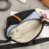A black and light blue nylon chest rig bag is shown open, displaying its interior lining and strap.