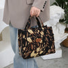 A woman holds a large capacity cloth tote bag with a brown and black leopard print pattern.