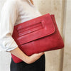 A woman holds a deep red leather sequined crossbody clutch bag against a light background.