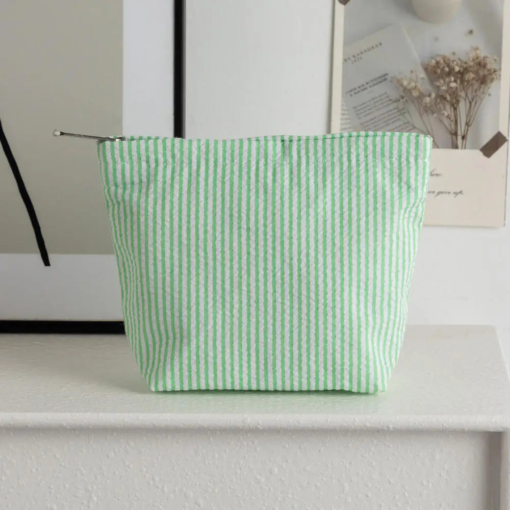 Clutch de rayas verde claro sobre una superficie blanca junto a una foto enmarcada.