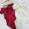 A pair of elegant silk bows in deep red and cream colors displayed next to a card.