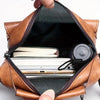 Un sac bandoulière en cuir PU marron ouvert, montrant une carte de crédit argentée et une casquette noire à l'intérieur.