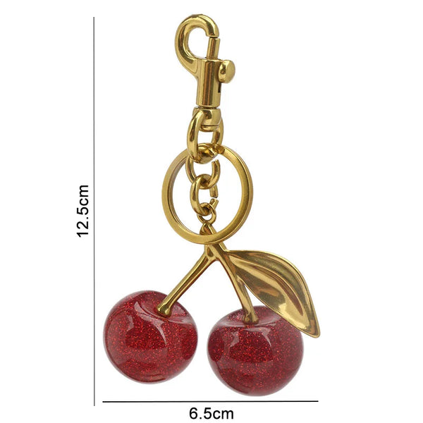 Gold-colored crystal apple charm keychain with a loop and leaf detail