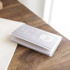 A triple pack of frosted clear card sleeves for ID and credit cards resting on a wooden surface.