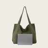 A large olive green canvas shoulder tote bag is shown next to a silver tablet.