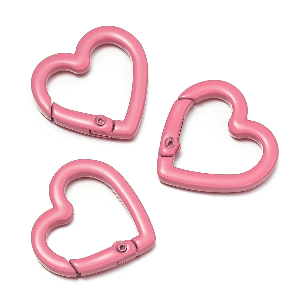 Two pink heart-shaped metal spring clasps are shown against a white background.