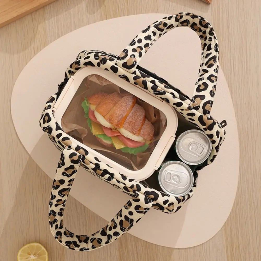 A leopard print insulated lunch tote bag with a clear compartment holding a sandwich and a can.