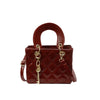 A maroon diamond grid textured leather crossbody bag with a brown handle and gold hardware.
