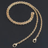 A gold-colored adjustable metal chain strap for a crossbody bag, laid out against a dark background.