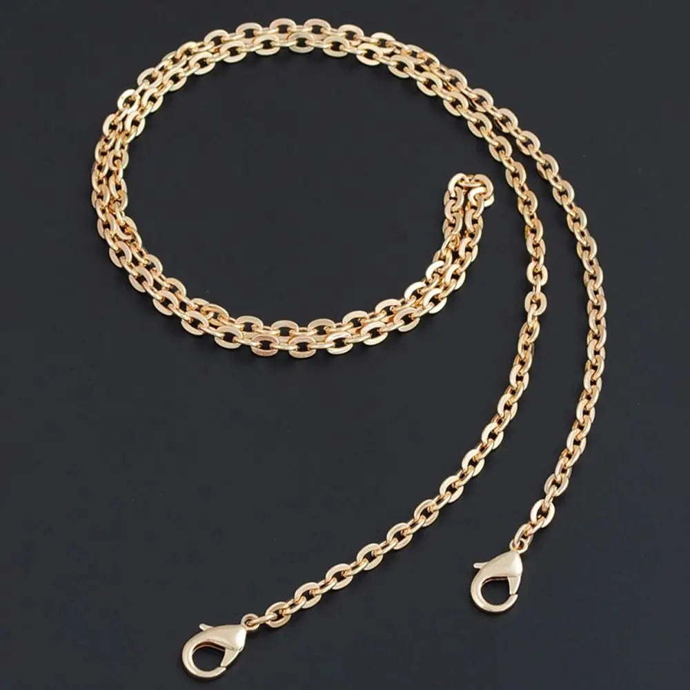 A gold-colored adjustable metal chain strap for a crossbody bag, laid out against a dark background.