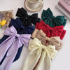 A collection of elegant silk bow hair clips in various shades including black, navy blue, purple, and olive green.