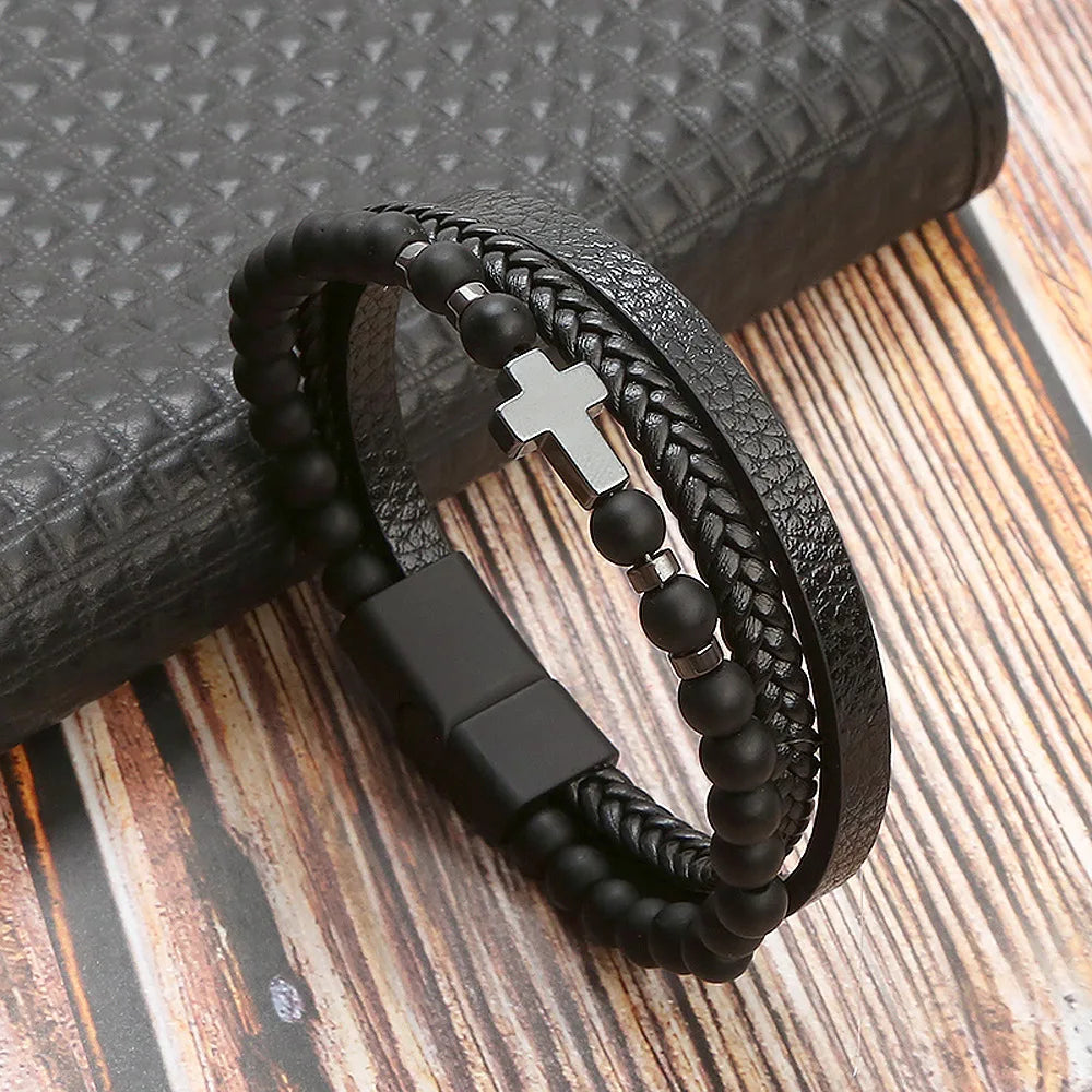 A black leather bracelet featuring a mix of braided leather and tiger eye beads resting on a wooden surface.