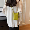 Camisa blanca oversize con bolso de cuero verde lima colgando del escote.